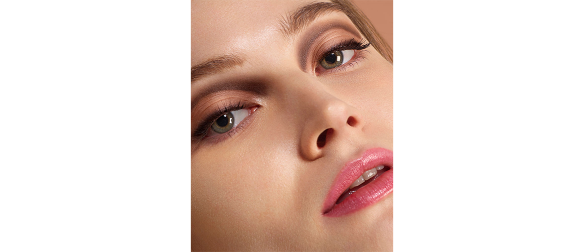 Geschminkte Frau mit goldenem Lidschatten und rosa Lippenstift